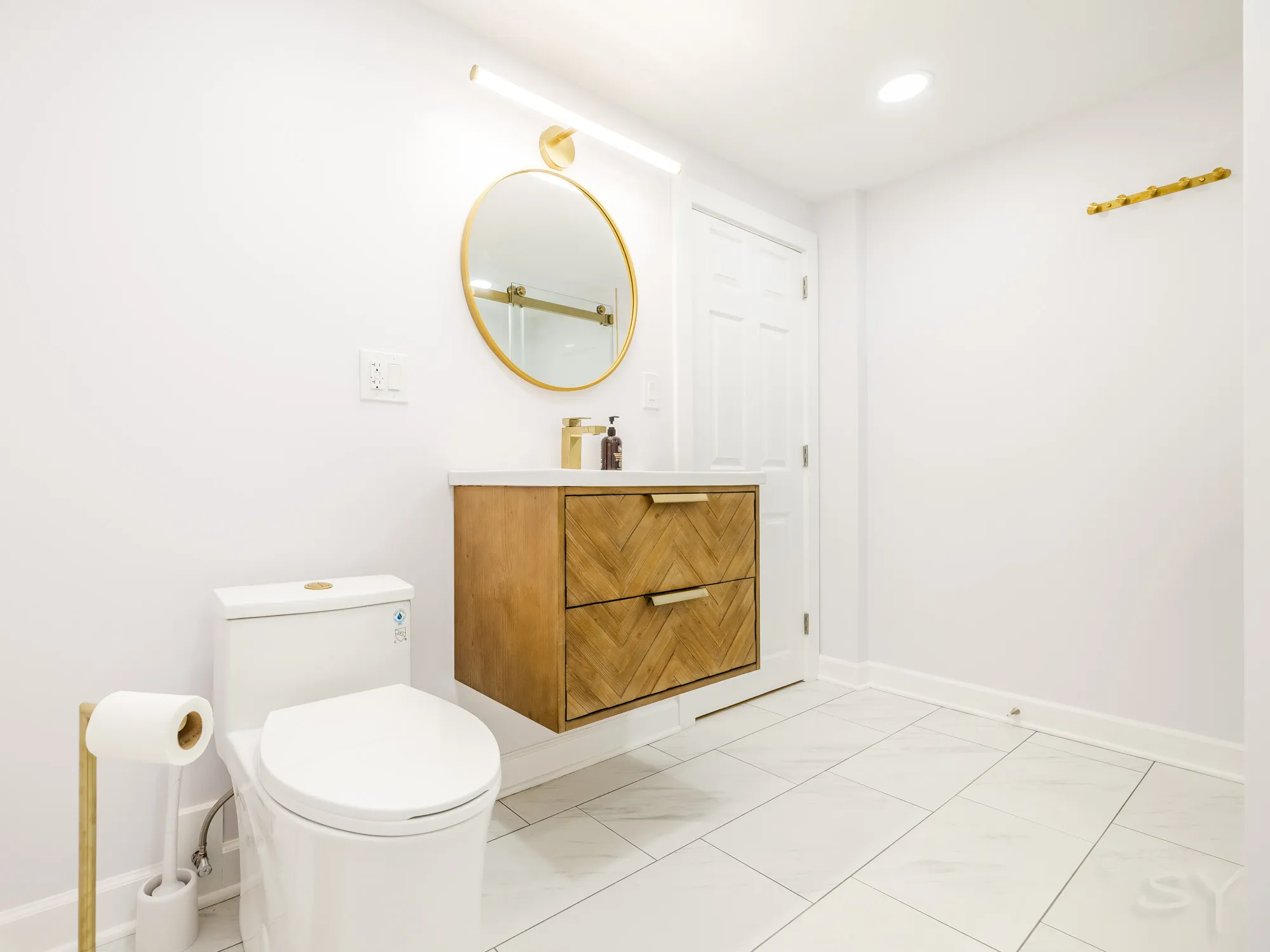 Bathroom with a floating wood vanity and gold round mirror