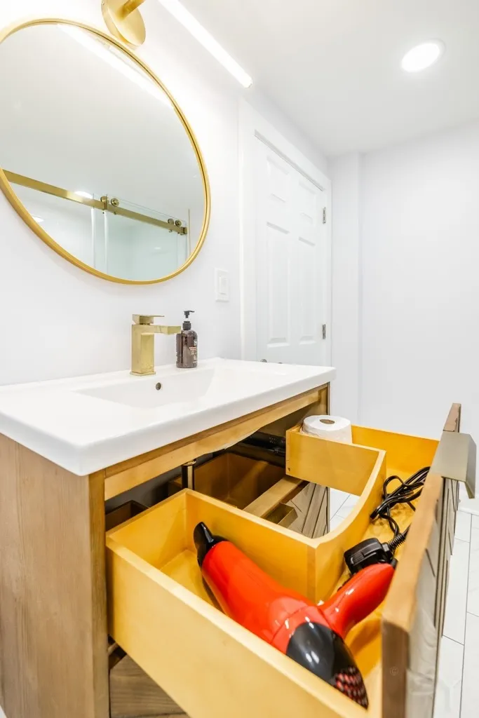 Bathroom vanity with a gold round mirror and glass shower