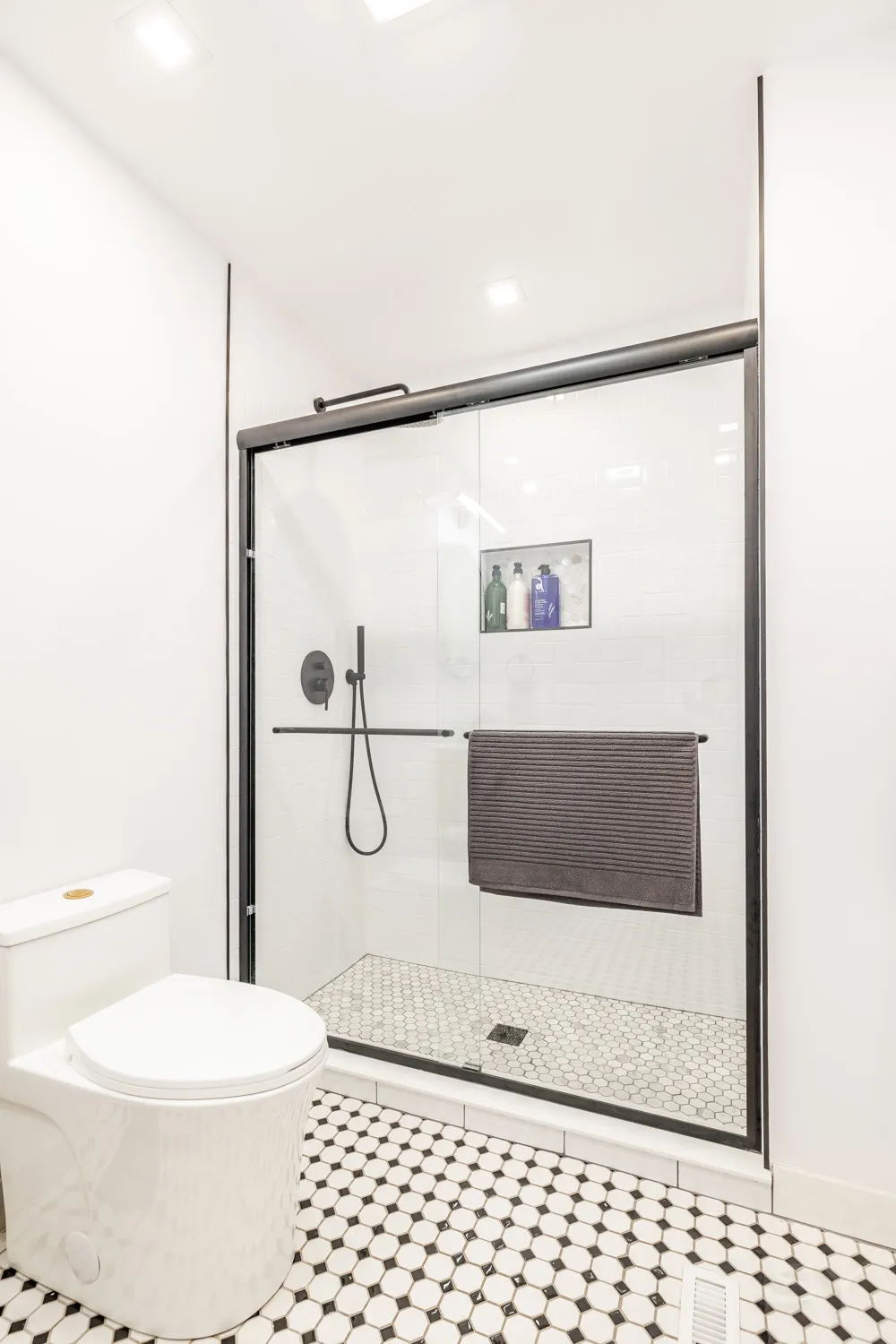 Walk-in glass shower with white subway tile and mosaic floor