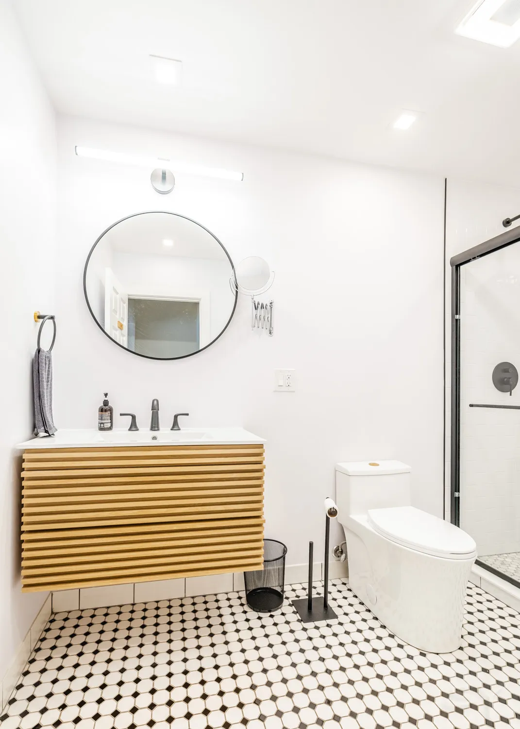 Bathroom with a floating wood-slat vanity and round mirror