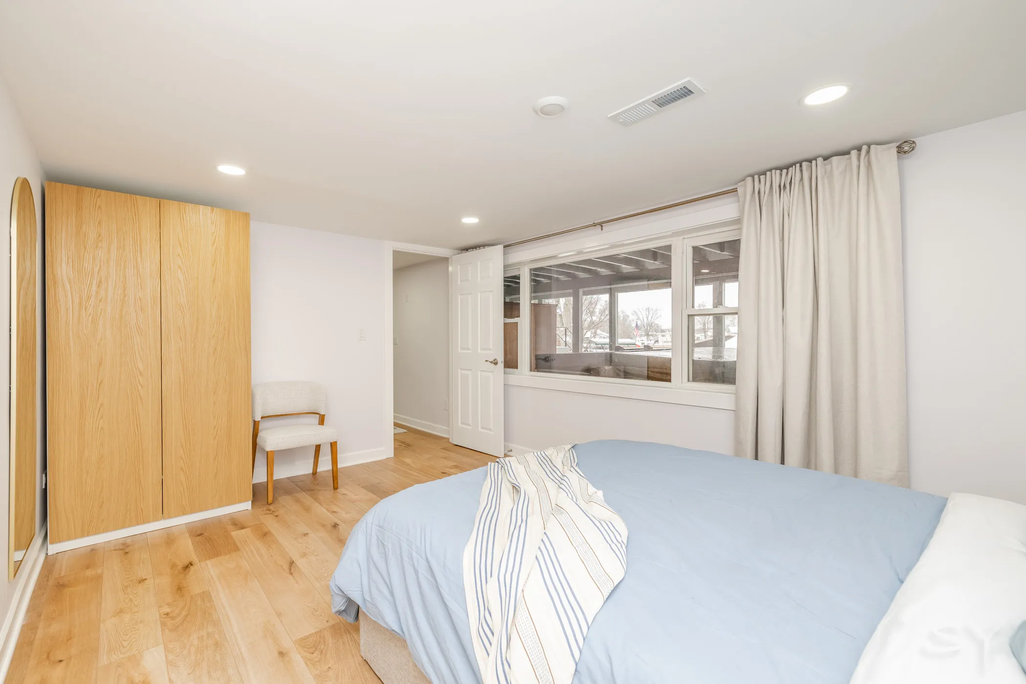 Queen bedroom with a wood wardrobe and accent chair