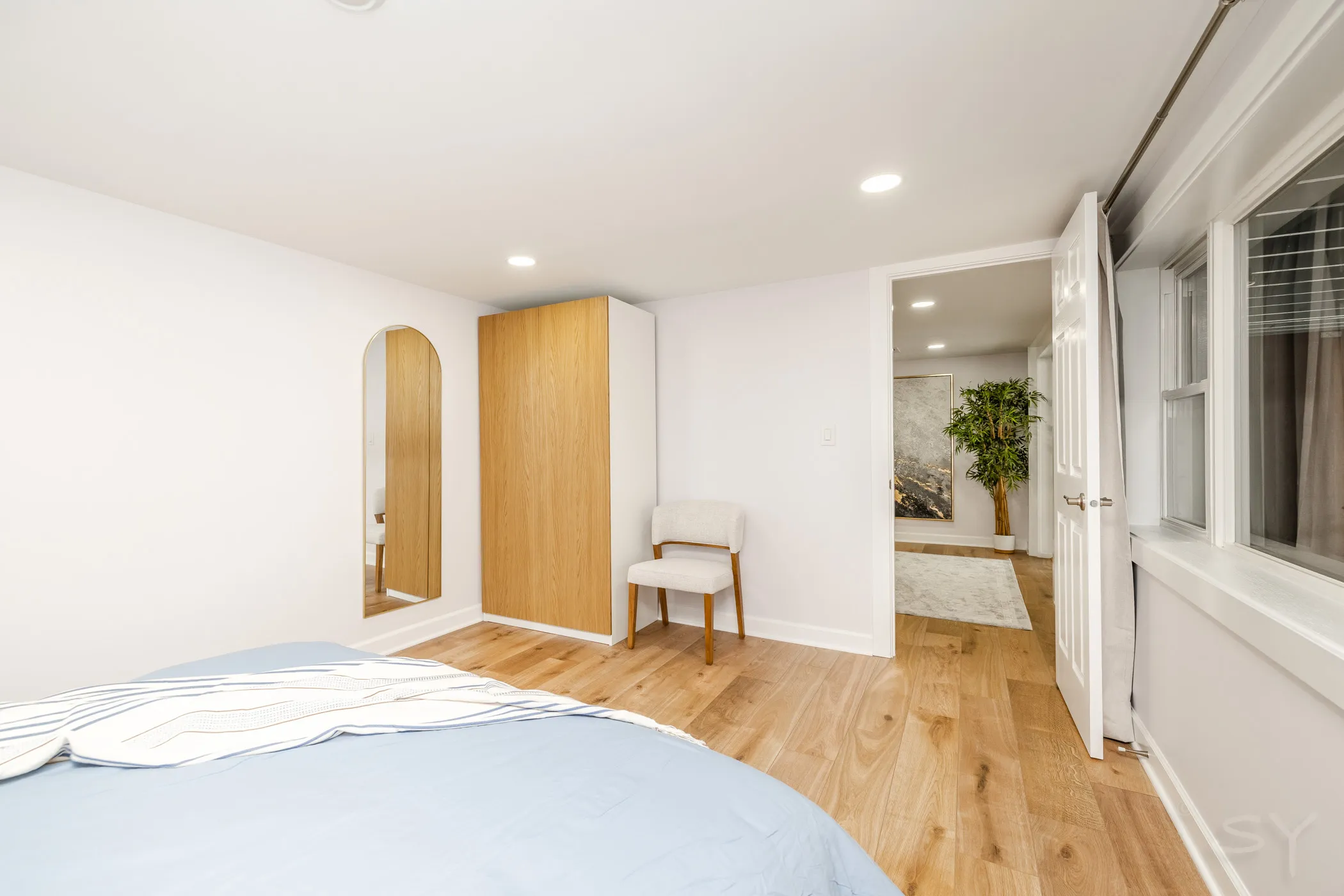 Queen bedroom with a wood wardrobe and arched mirror
