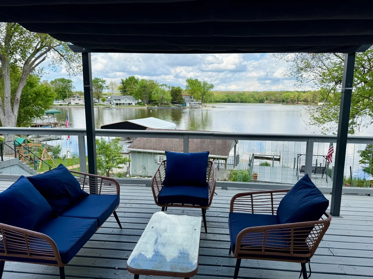 The lake house seen from the water, with its deck, dock and shade tree