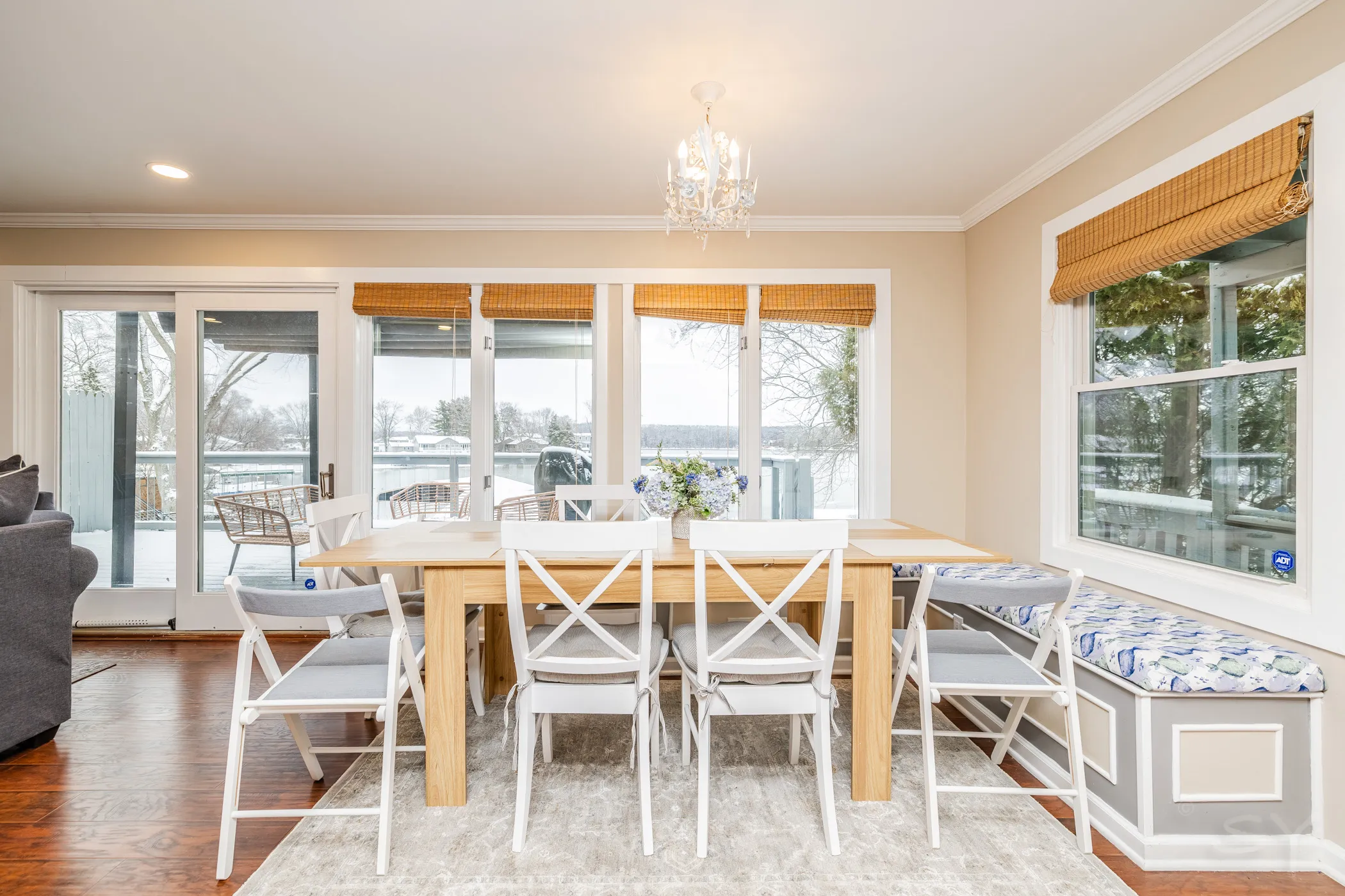 Large dining table and bench seating beside a wall of windows looking over the lake