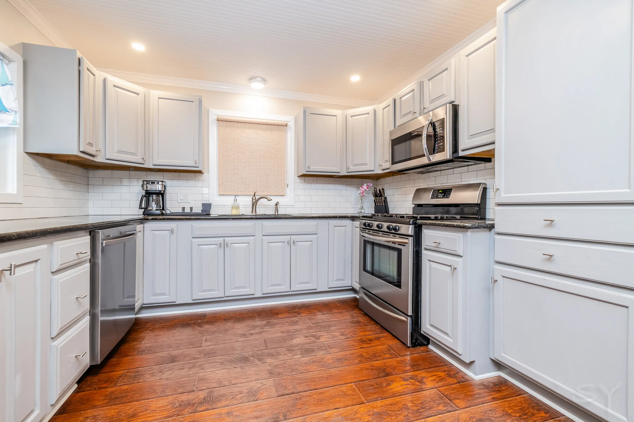 Kitchen with stainless gas range, granite counters and gray cabinetry