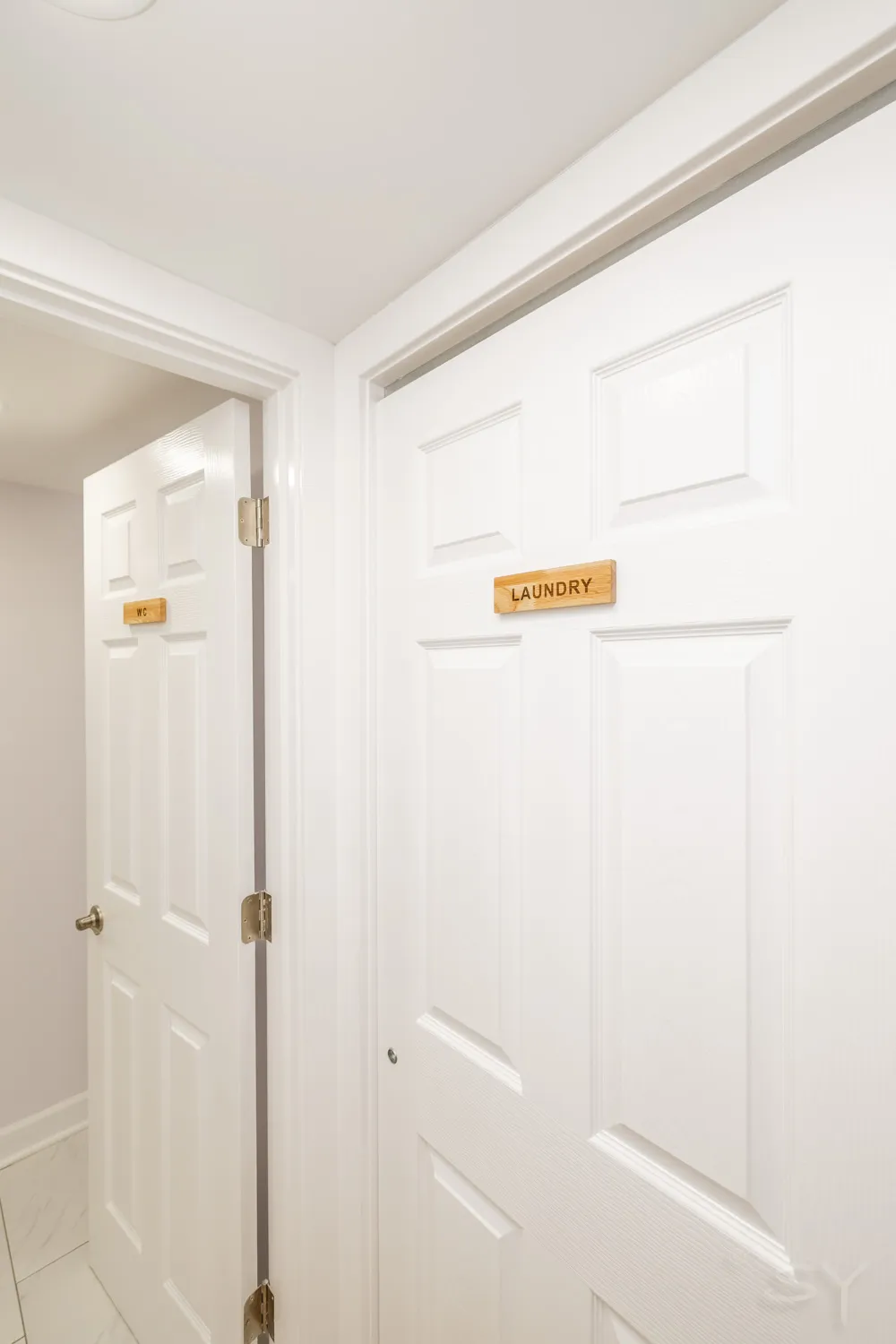 Hallway with labeled WC and laundry doors