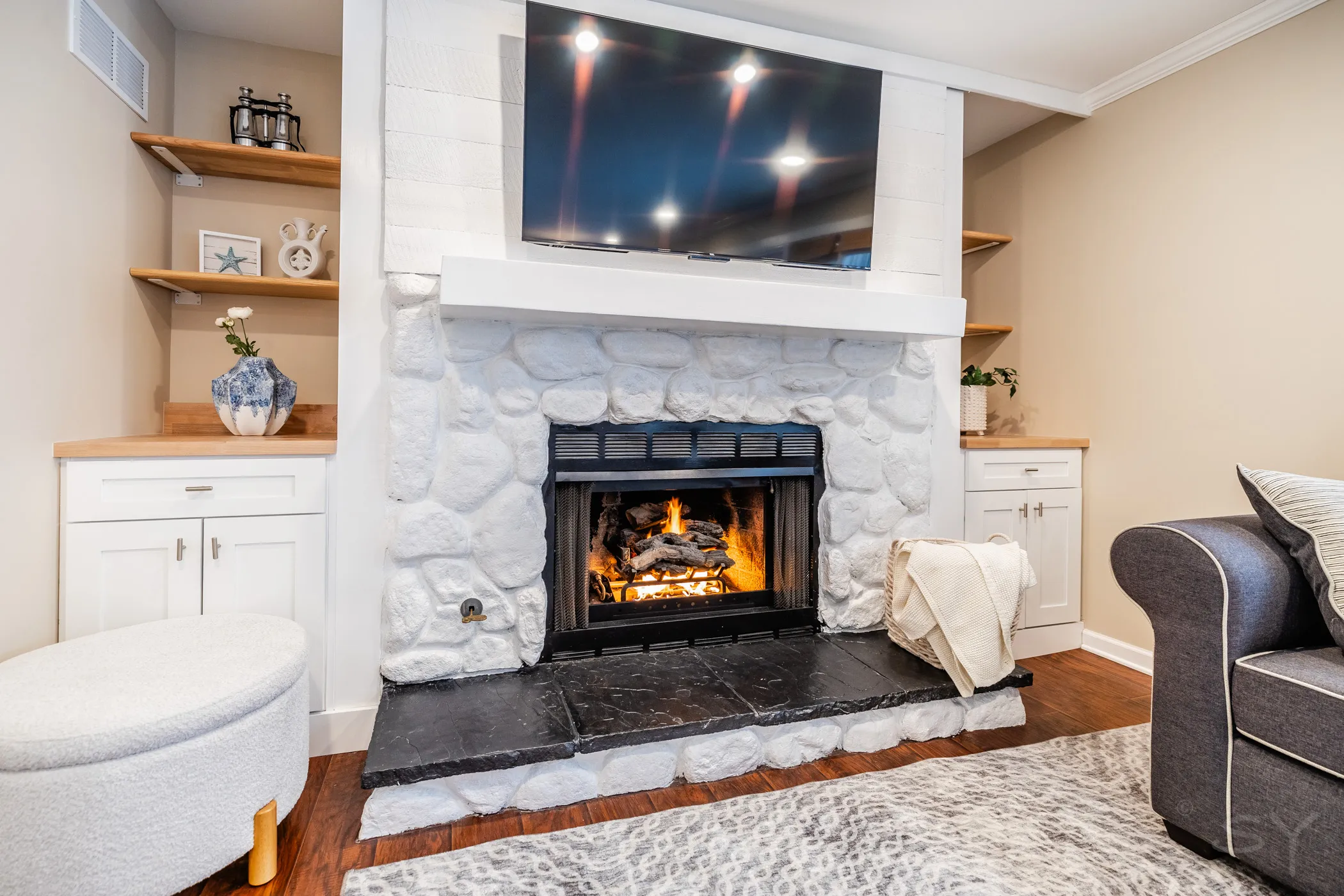 Living room with a lit stone fireplace, sofa and mounted TV