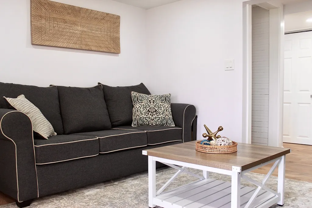 Lower-level lounge with a charcoal sofa and woven wall art