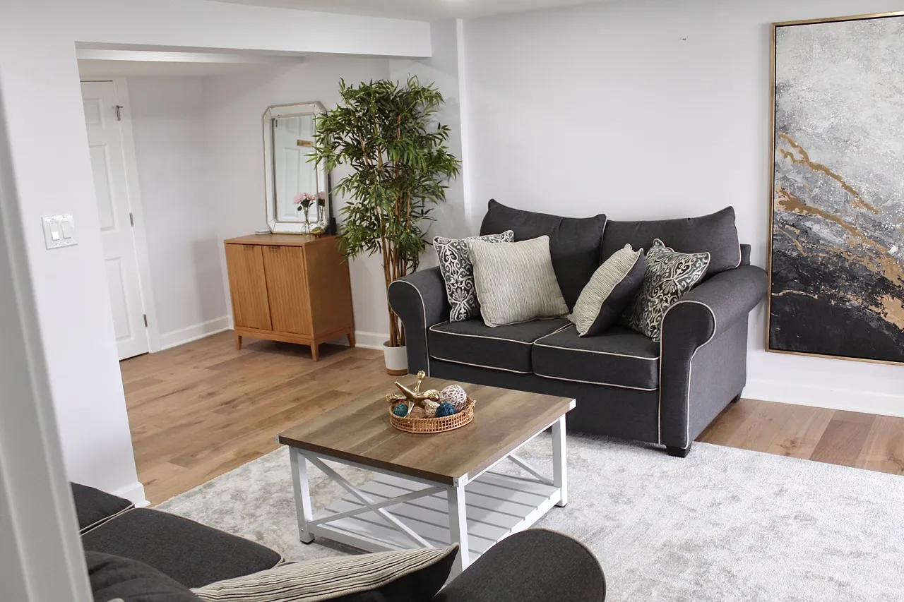Lower-level sitting room with a loveseat and large abstract art