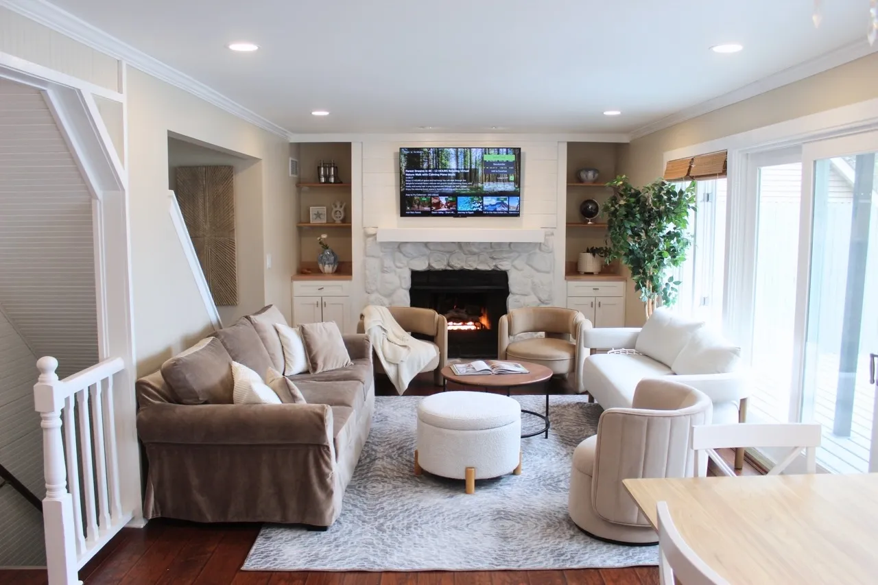 Living room with a stone fireplace opening to the dining table and patio doors